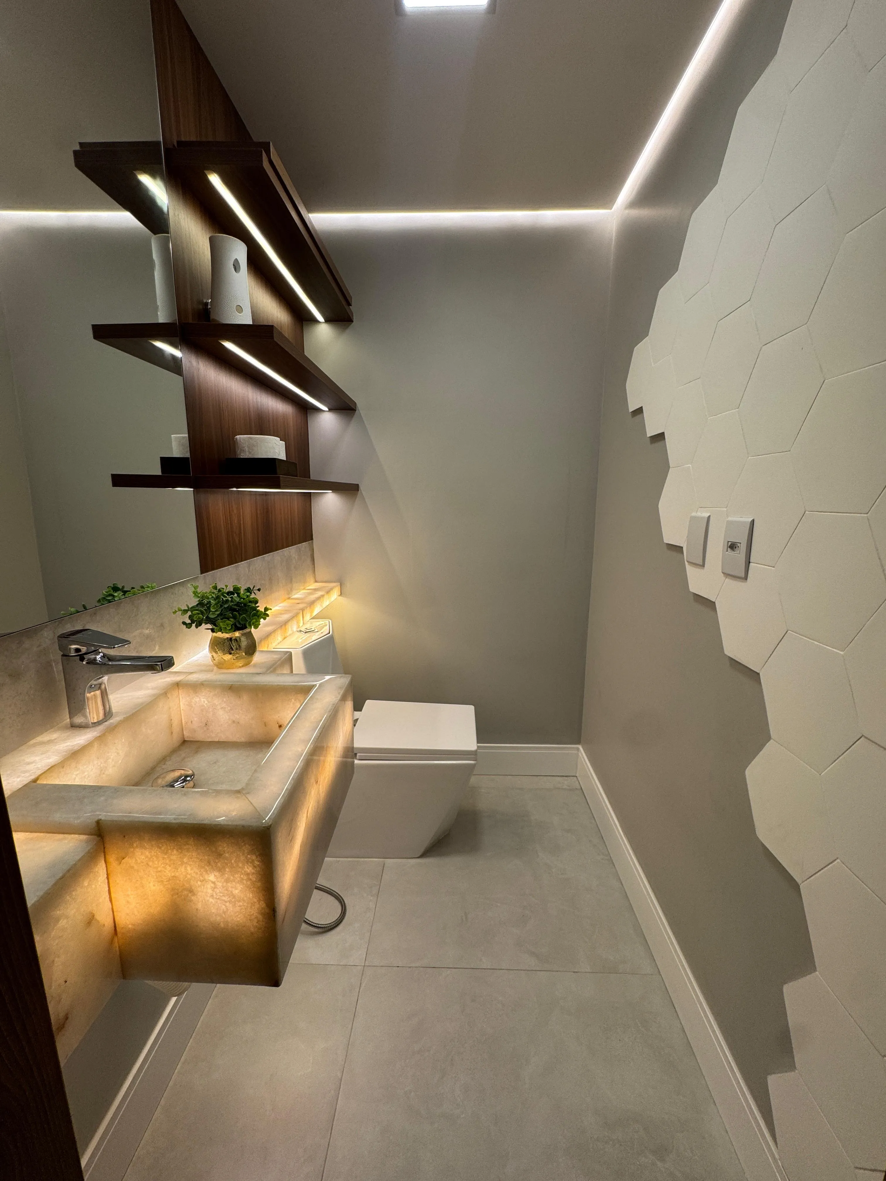 Lavabo com nicho de madeira iluminado e parede em hexágonos